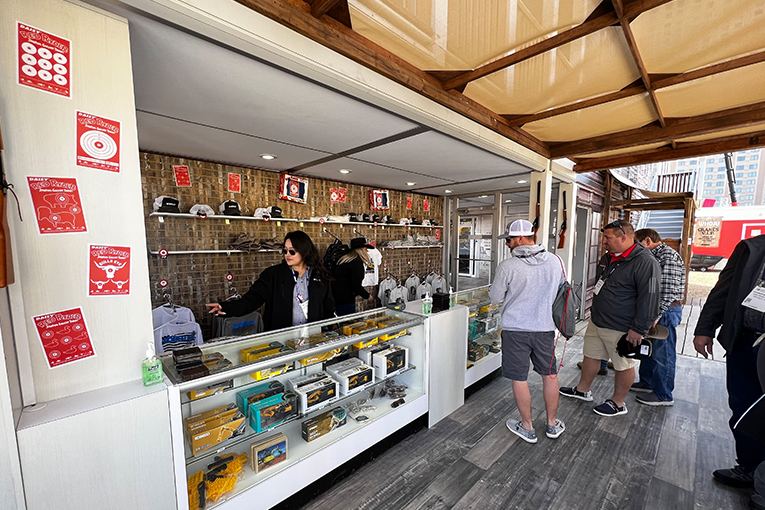 Visitors peering into shop cases while shopkeeper organizes the store.